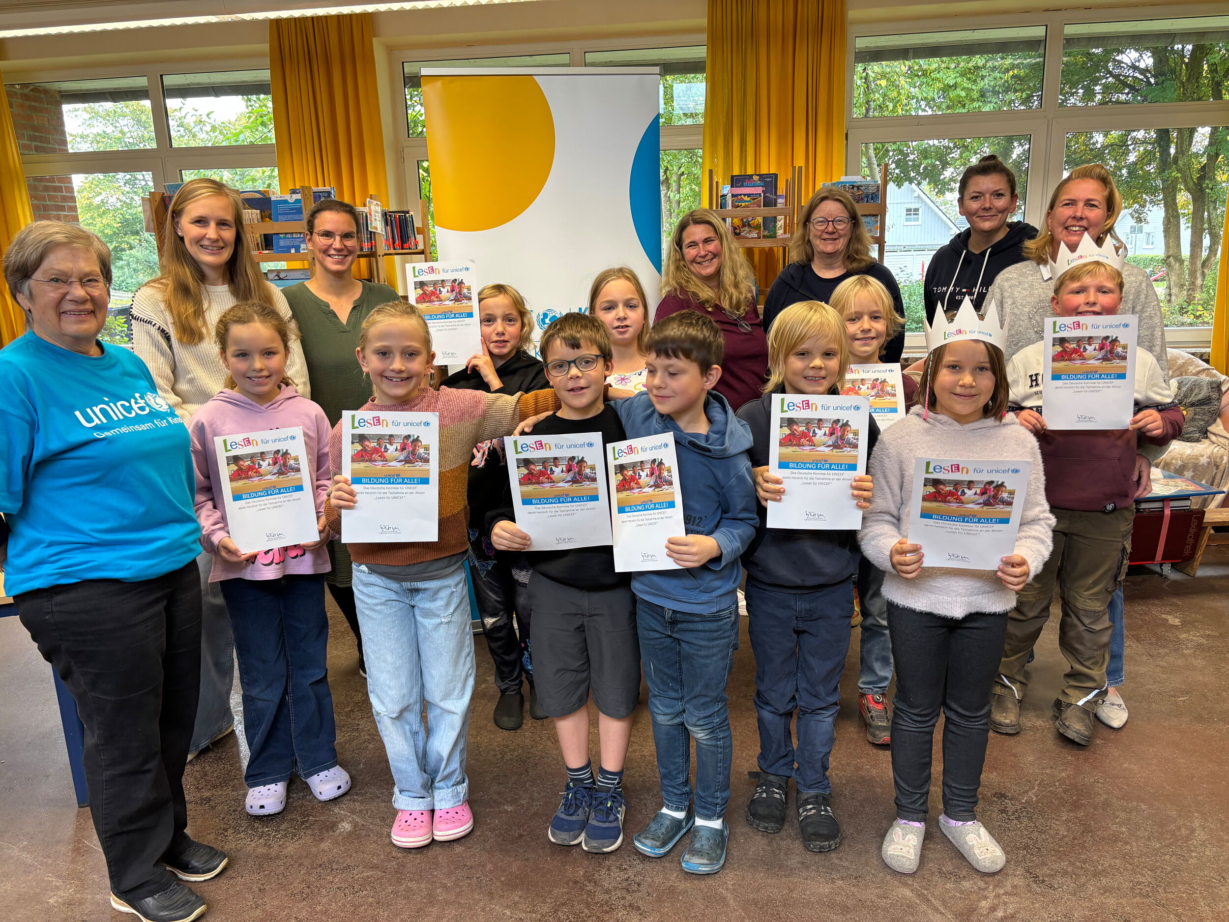 Kinder die am Projekt "Lesen für UNICEF" teilgenommen haben, halten ihre Urkunden hoch. Sowohl Lehrkräfte als auch Repräsentanten von UNICEF sind ebenfalls auf dem Foto.